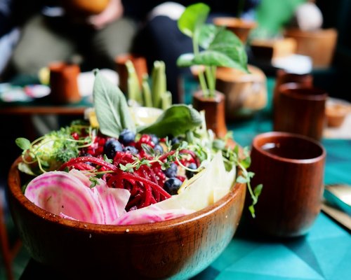 A vibrant assortment of fresh vegetables and fruits in a wooden bowl on a table.